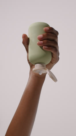 Close-Up-Of-Woman-Squeezing-Bottle-Of-Beauty-Product-Until-Contents-Squirt-Out-Shot-On-White-Background